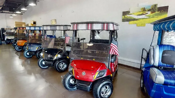 Village Elite Golf Cars showroom with a row of Yamaha golf carts, a red cart and a blue custom cart in front